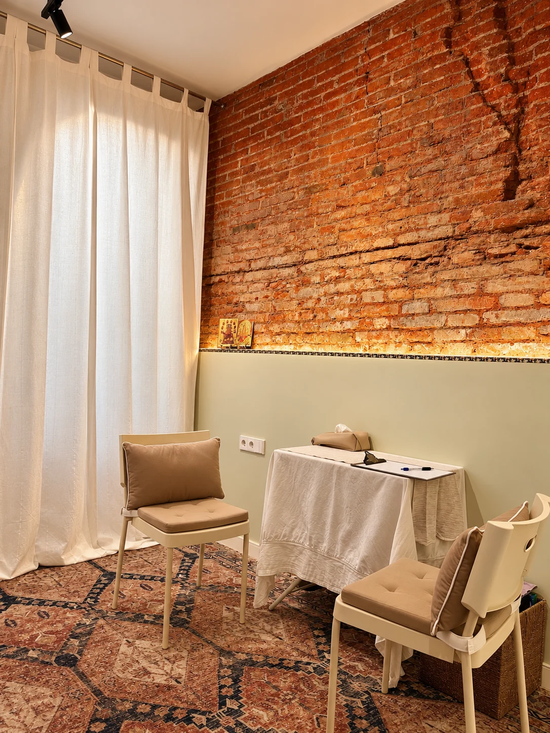 Espacio de consulta en Barcelona, con dos sillas y una mesa junto a una pared de ladrillo